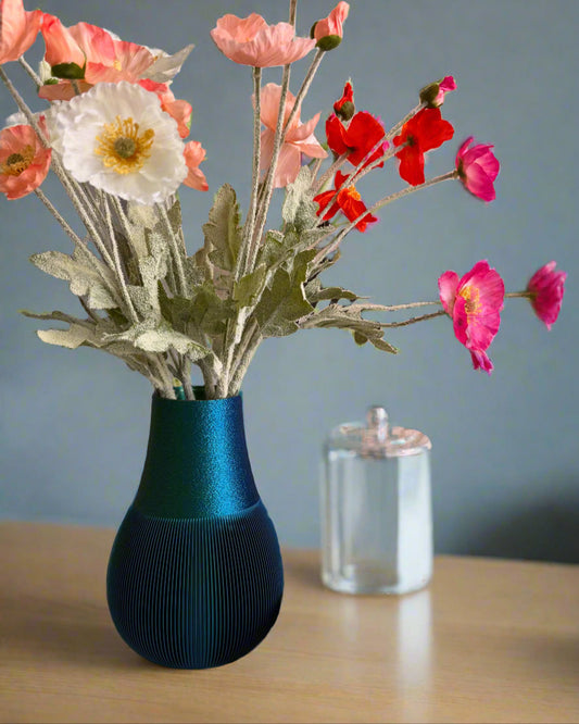 Blue textured vase with colourful flowers on a wooden surface against a grey background